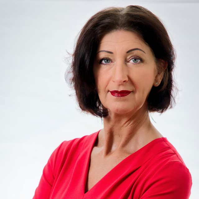 Carmen Lehner, professionelles Porträt im roten Kleid vor hellem Hintergrund.
