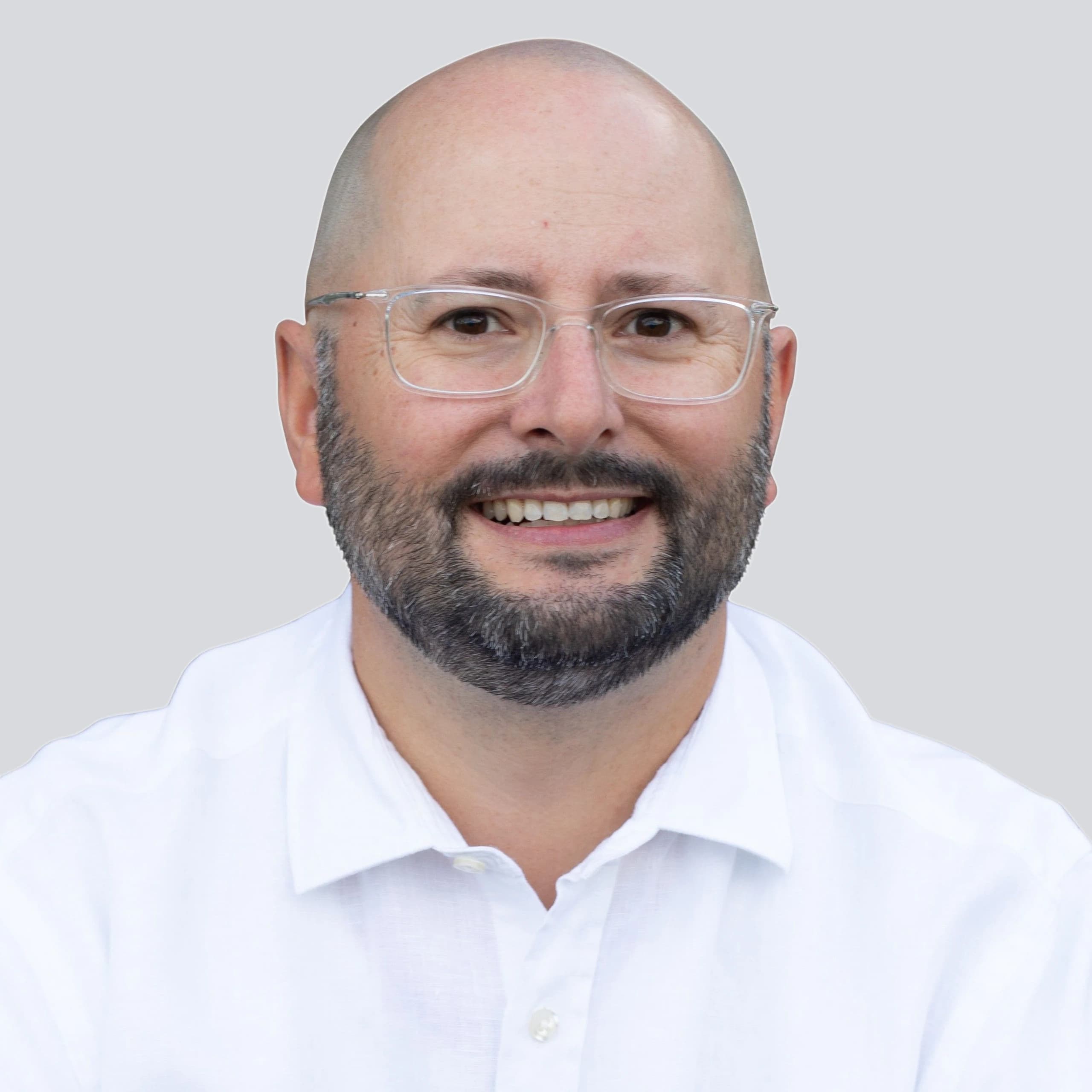 Dr. Jens Träger, lächelndes Porträt im weißen Hemd vor hellgrauem Hintergrund.