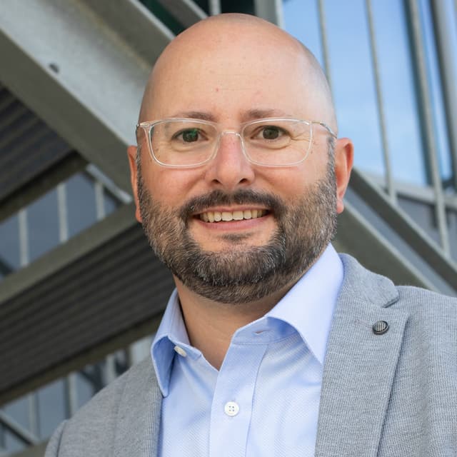 Dr. Jens Träger, professionelles Porträt im hellgrauen Sakko und Hemd.